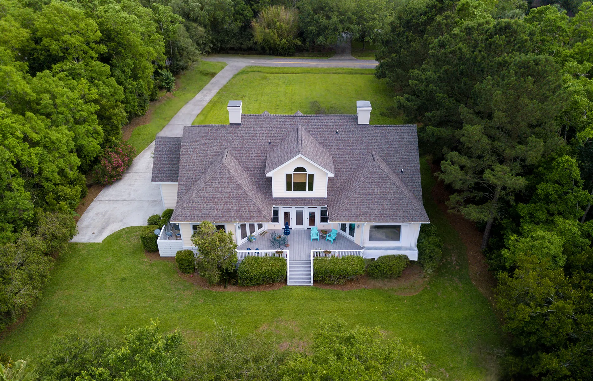 A house with a new roof and porch surrounded by lush green woods and lawn.