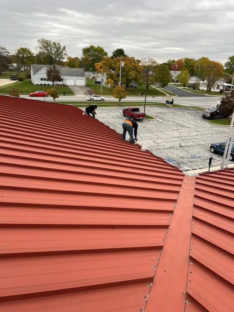 Repairing fasteners on a red metal commercial roof